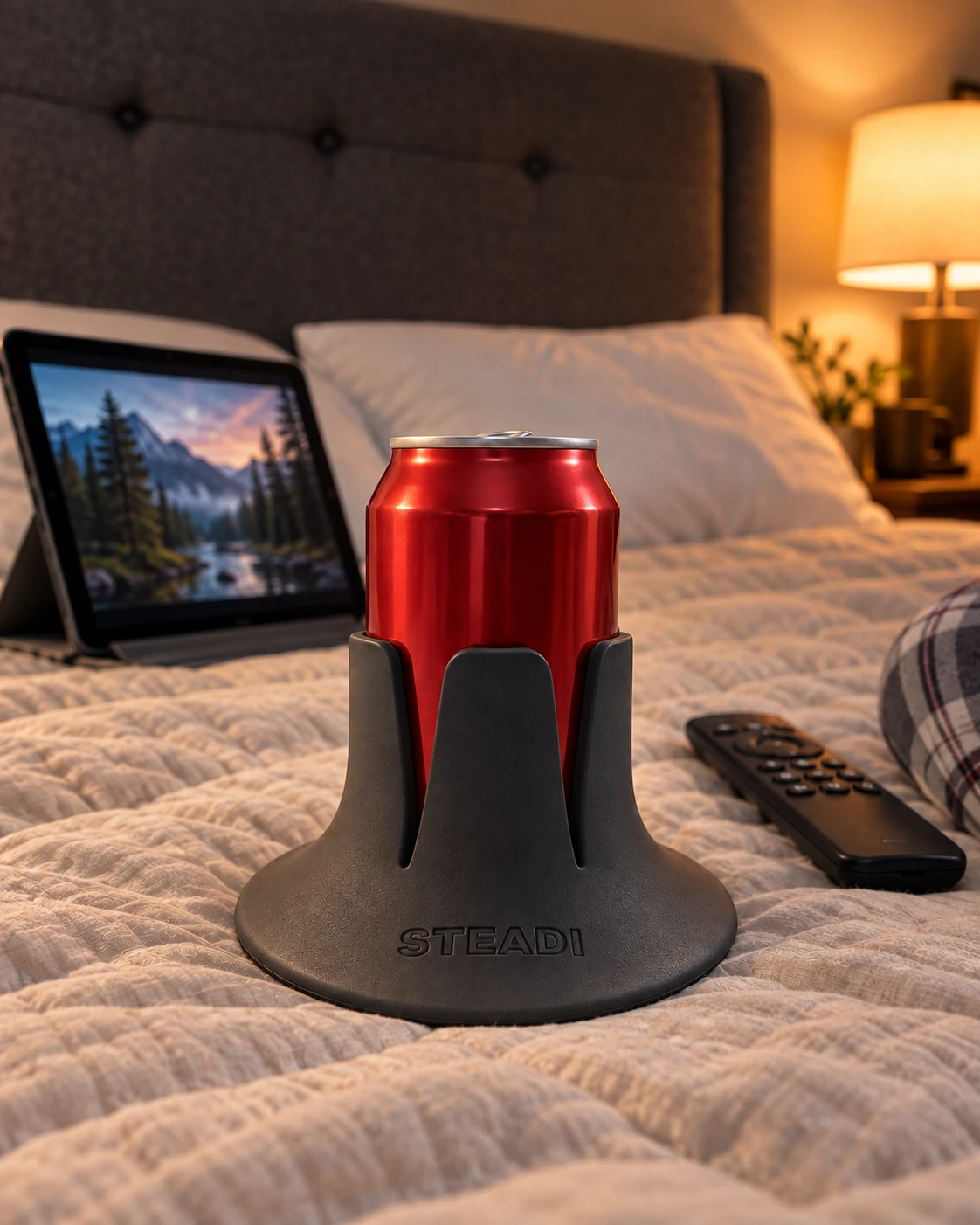 Opened red can in a Charcoal Steadi on bedding beside a tablet and remote. AI lifestyle image.